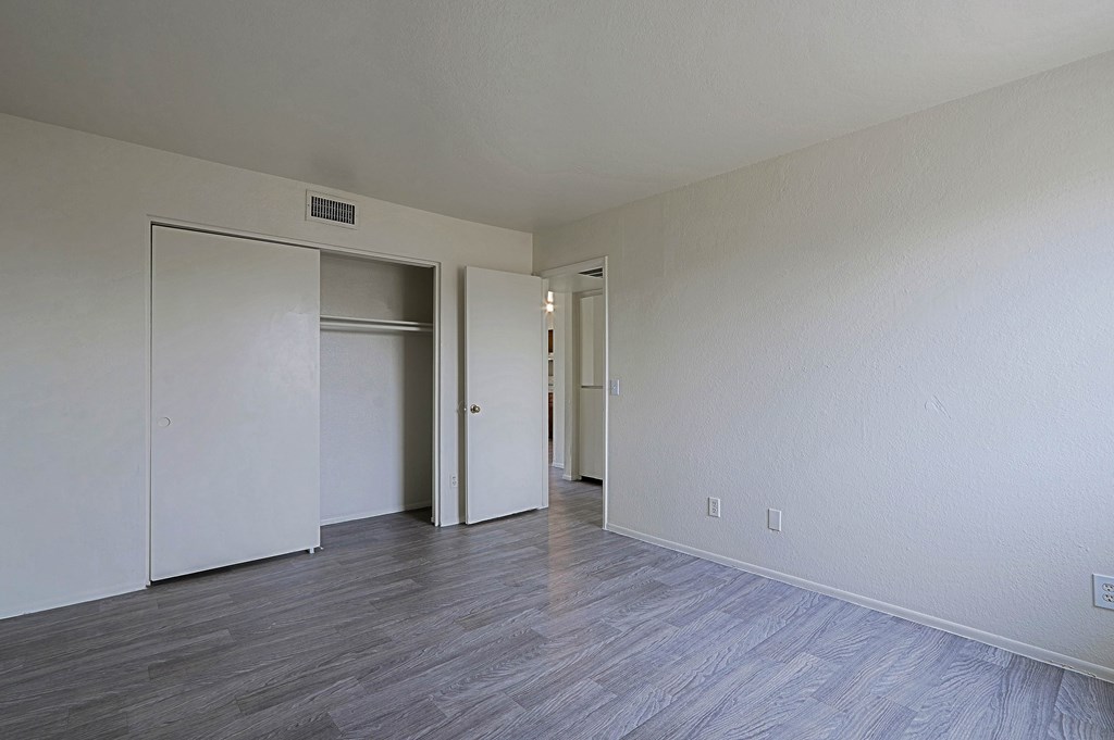 A room with a white wall and a grey floor with a white door and a white wardrobe.
