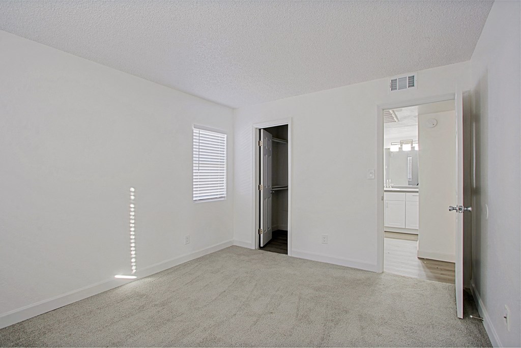 an empty living room with a door to a bathroom