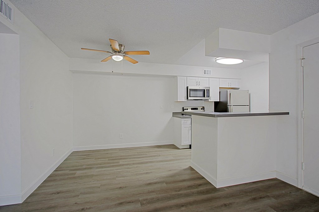 an empty apartment with a kitchen and a ceiling fan