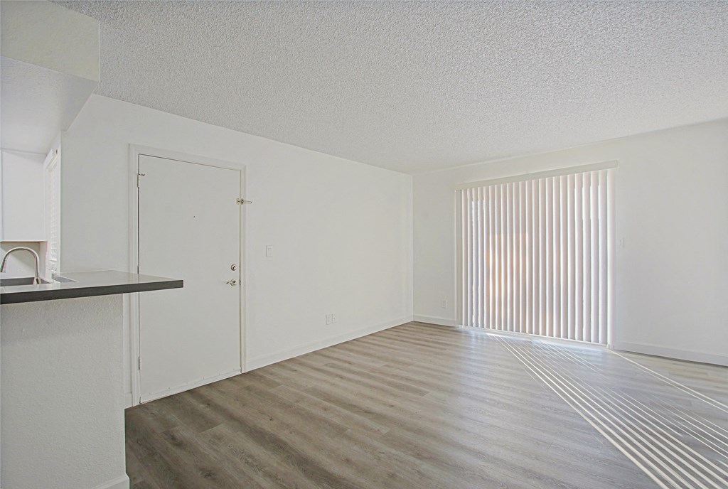 an empty living room and kitchen with white walls and wood flooring