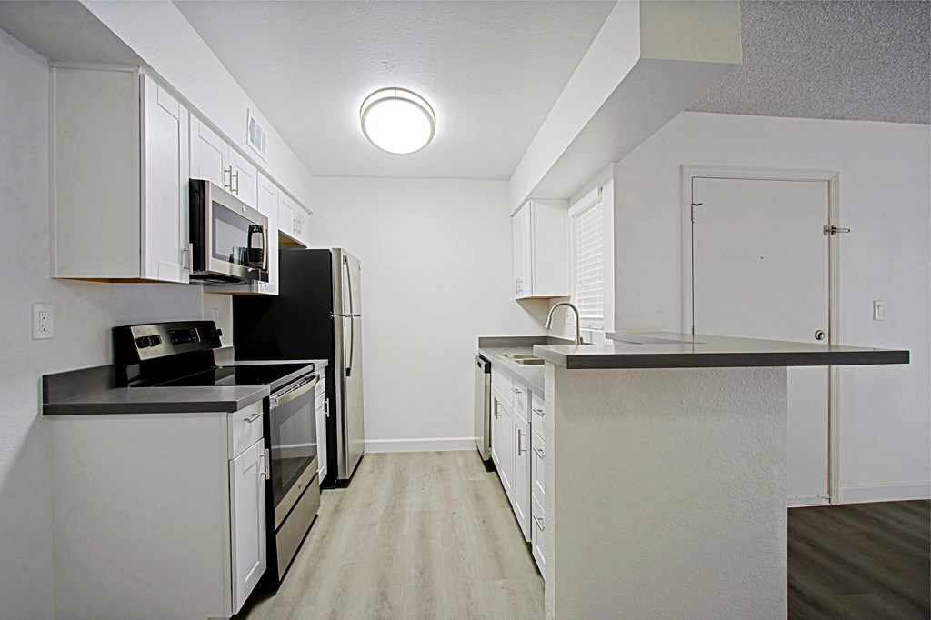 an empty kitchen with white cabinets and black counter tops
