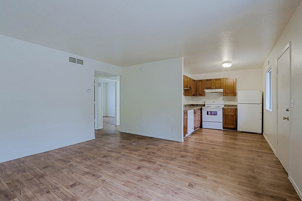 A kitchen with white appliances and wooden floors.