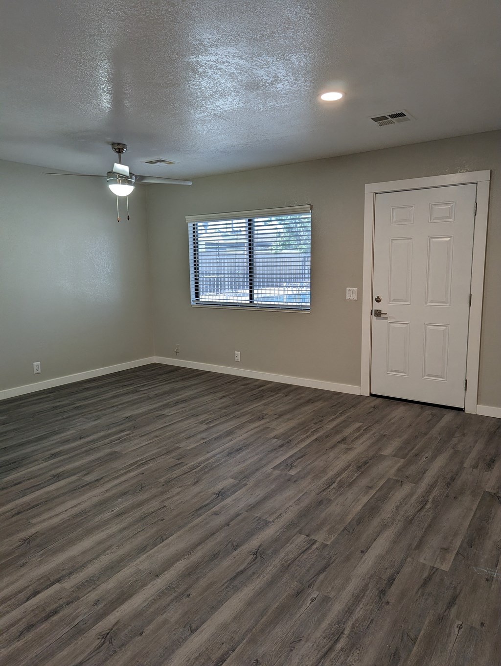 an empty living room with wooden floors and a white door