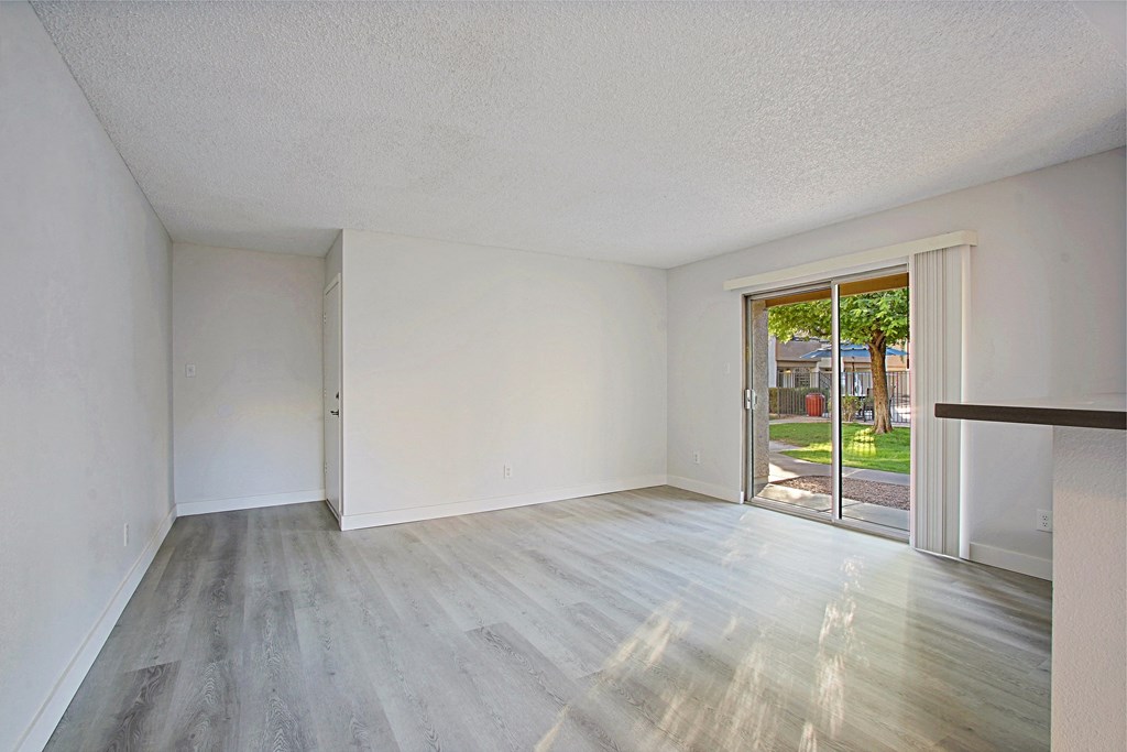 an empty living room with a sliding glass door to a patio