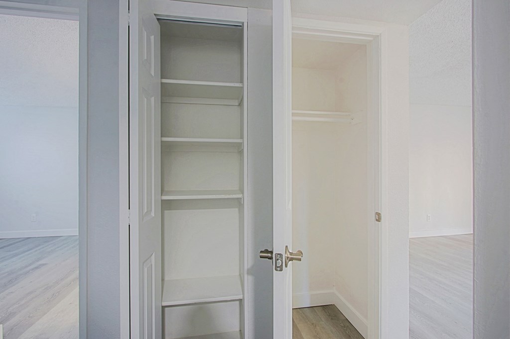 an empty room with white closet doors and a wood floor