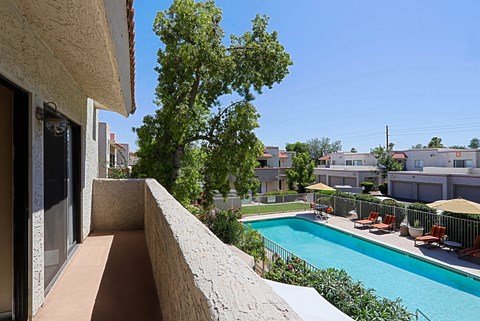 A pool with chairs and a tree in the background.