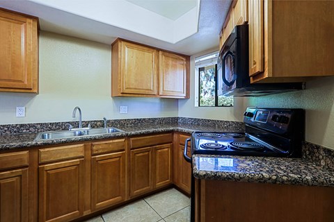 A kitchen with wooden cabinets and granite countertops.
