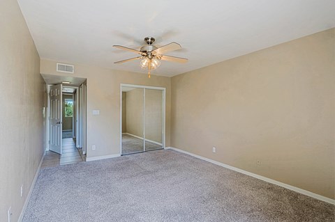 A room with a ceiling fan and carpeted floor.