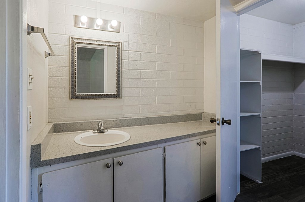 A bathroom with a sink, mirror, and cabinets.