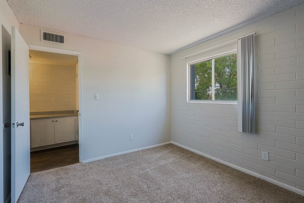 A room with a window and a door leading to a kitchen.