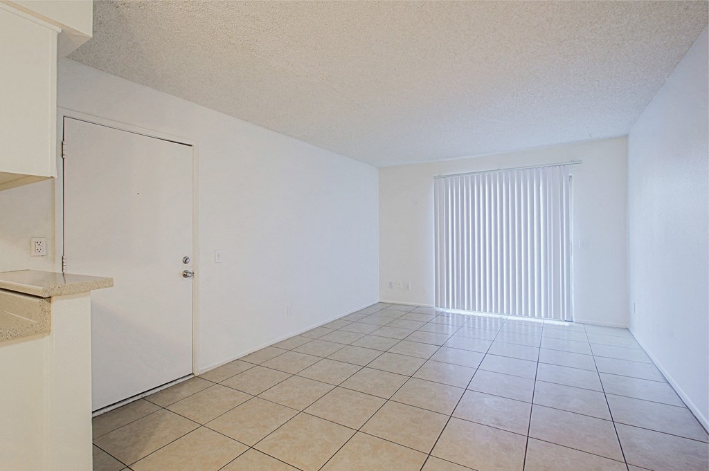 the living room and dining room of an apartment with a tiled floor