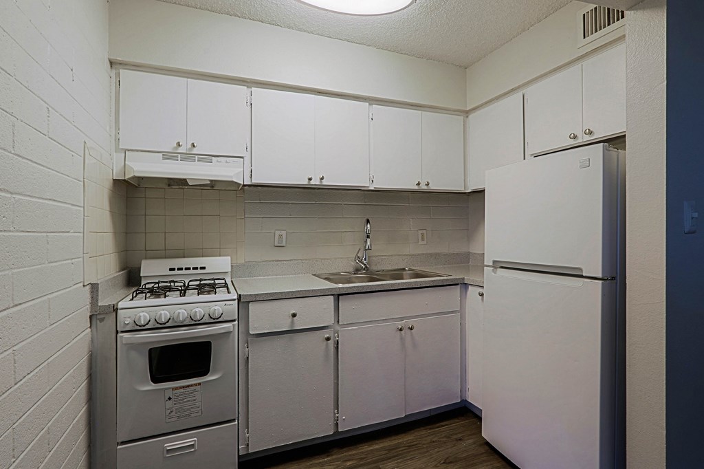 A small kitchen with a stove, sink, and refrigerator.