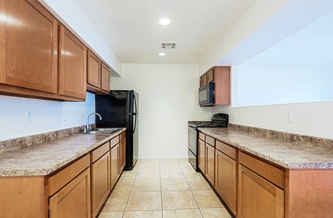 A kitchen with brown cabinets and granite countertops.