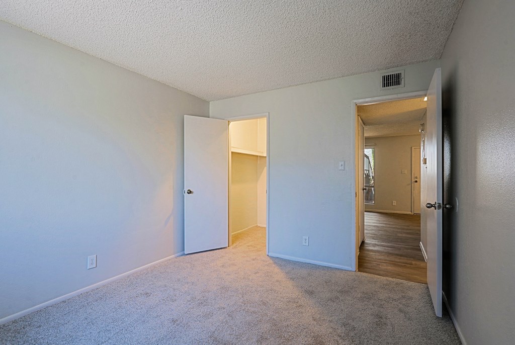 A room with a carpeted floor and two open doors.