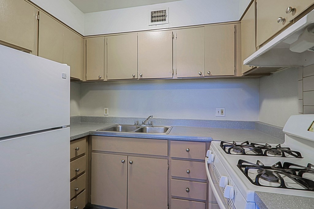 A kitchen with a white fridge, a white stove, and a sink.