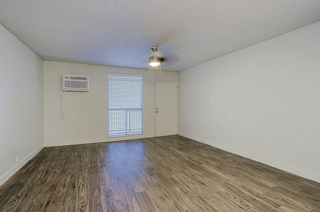 A room with wooden flooring and a window with blinds.
