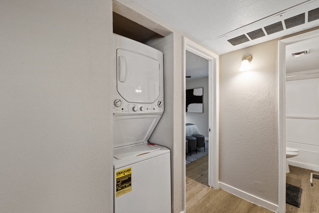 A small white washing machine is in a narrow space between two walls.