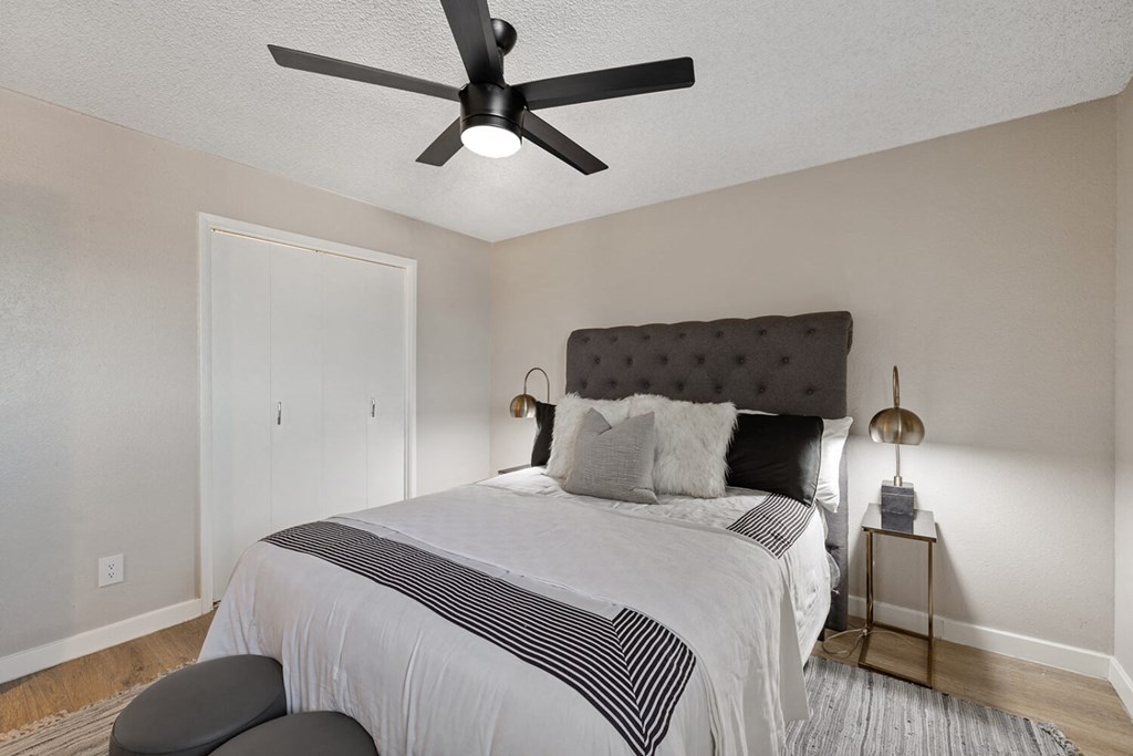 A bedroom with a bed, pillows, and a ceiling fan.