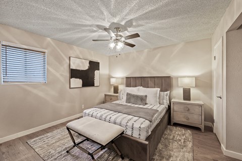 A bedroom with a bed, chair, and ceiling fan.