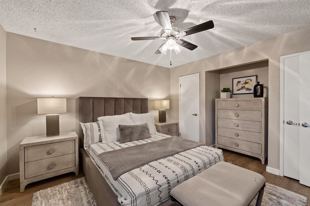 A bedroom with a bed, nightstand, and dresser.