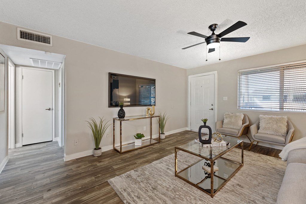 A living room with a glass coffee table and a flat screen TV mounted on the wall.
