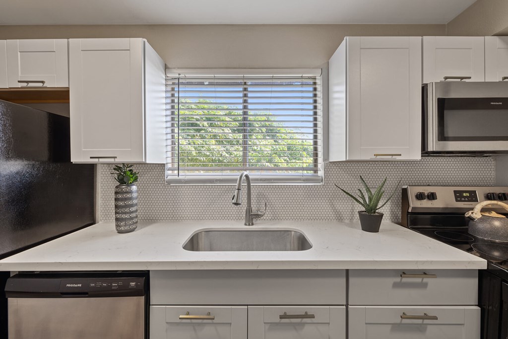 A kitchen with white cabinets and a black dishwasher.