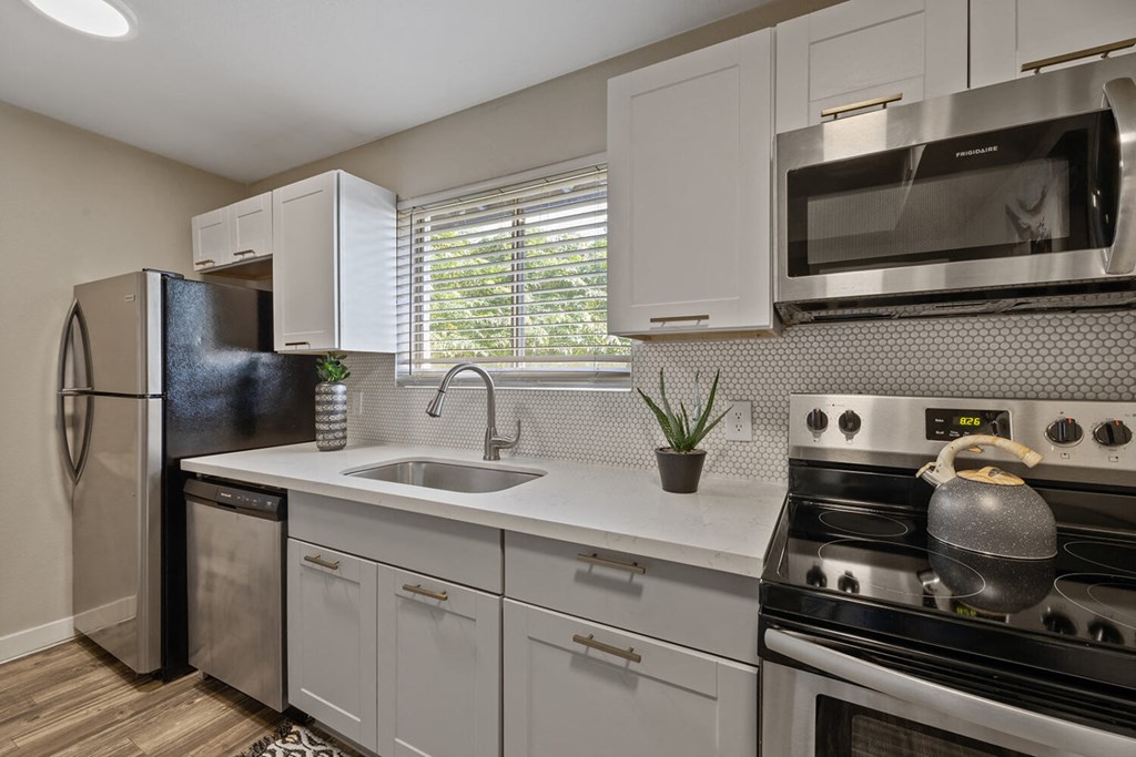 A modern kitchen with white cabinets and stainless steel appliances.