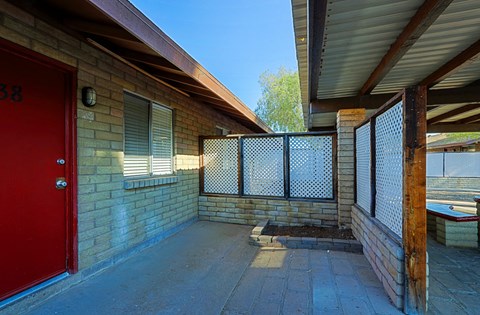 A red door is on the left side of a brick building.