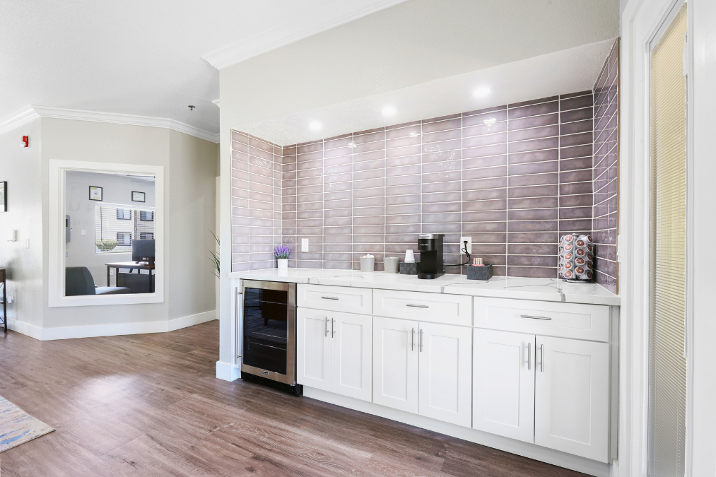 A kitchen with white cabinets and a brick wall backsplash.