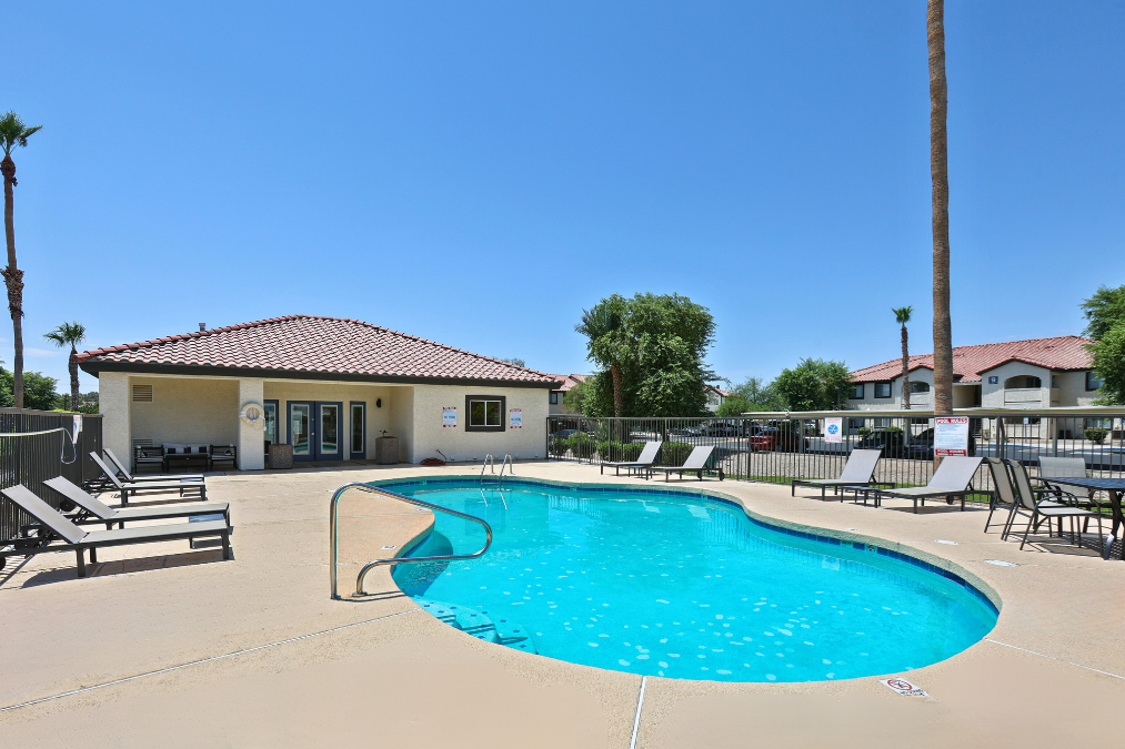 A swimming pool with lounge chairs and a building in the background.
