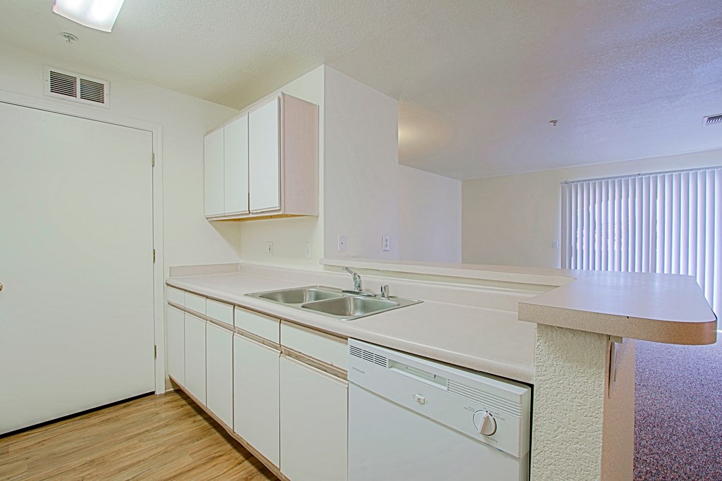 A white kitchen with wooden floors and a dishwasher.