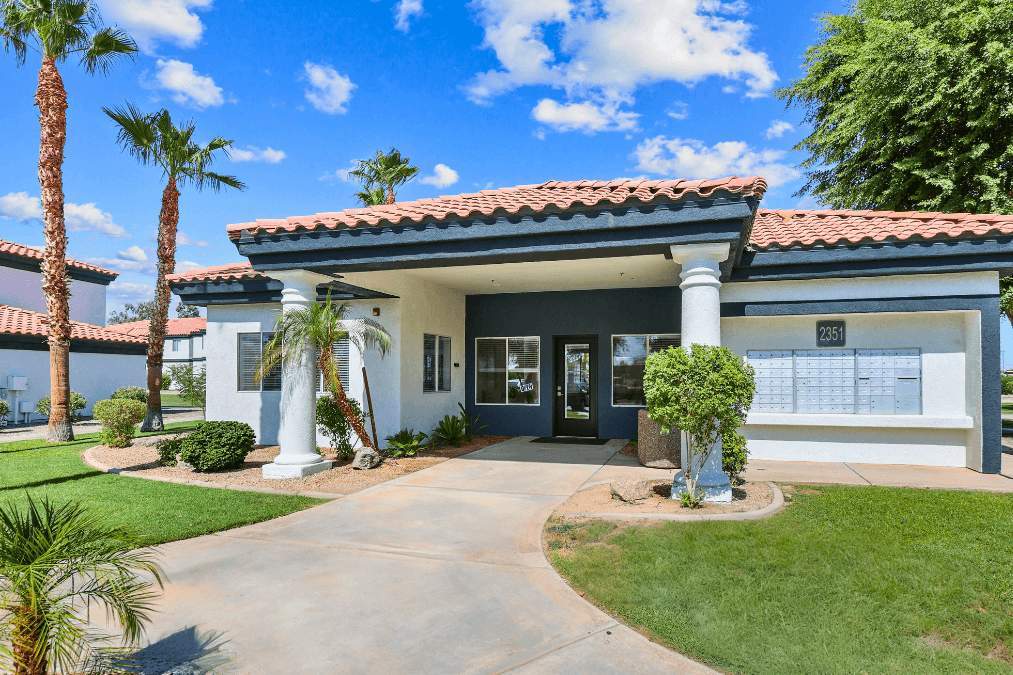 a house with a driveway and palm trees in front of it