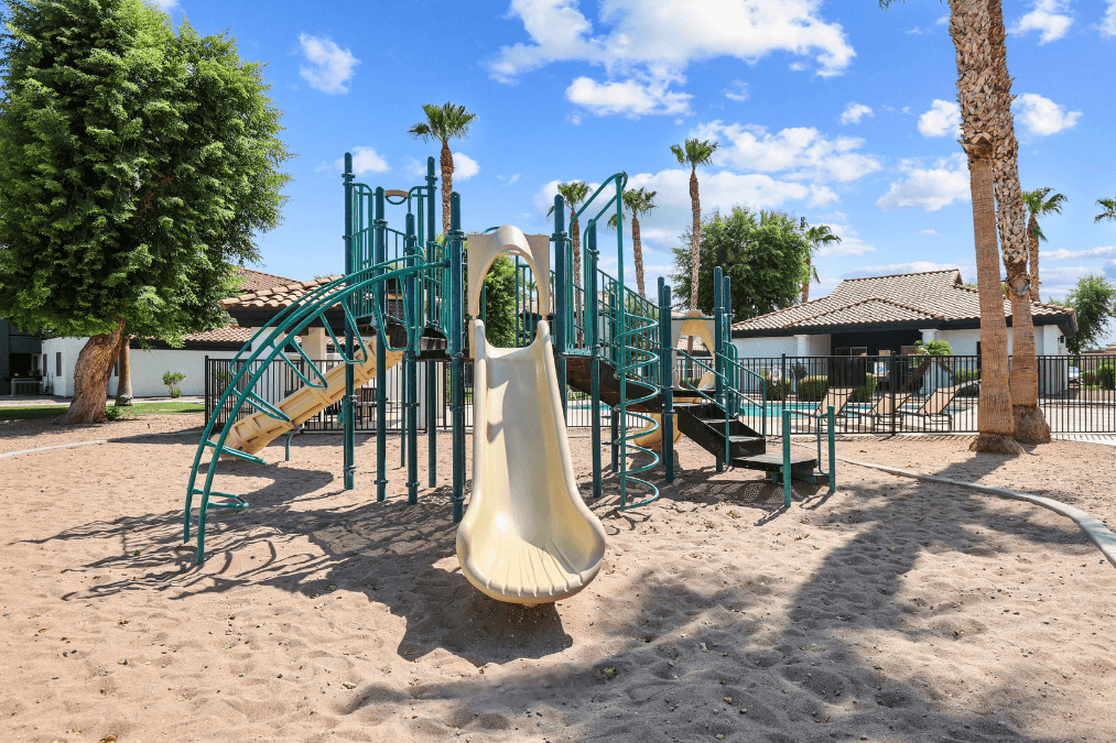 a playground with a slide in the middle of the sand