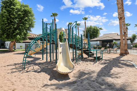 a playground with a slide in the middle of the sand