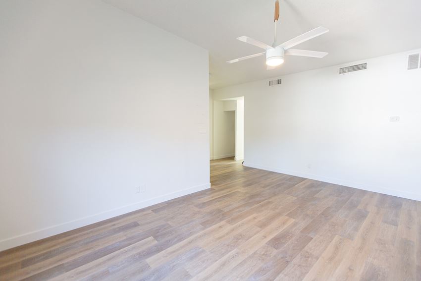 an empty living room with white walls and wood floors