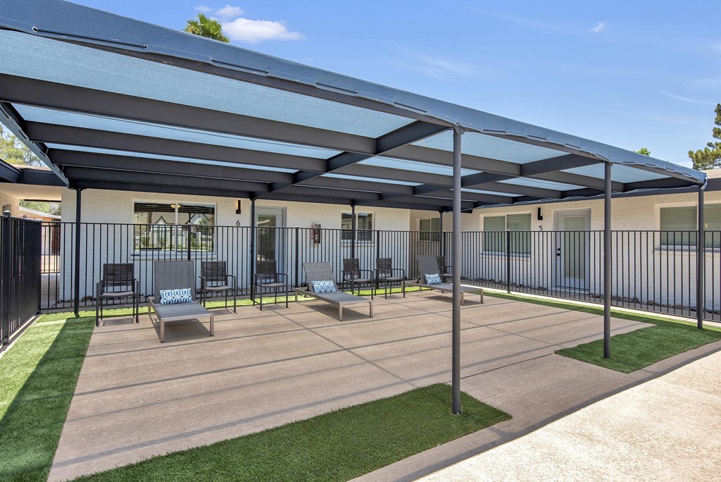 a patio with chairs and awning in front of a building