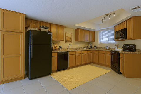 A kitchen with wooden cabinets and a black fridge.