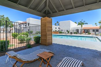 Stylish cabana with two wooden chaise lounge chairs with blue and white stripped covers facing the pool at Tides at Mesa, Mesa, Arizona