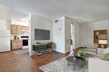 A living room with a couch, a coffee table, and a television at Foothills Court Apartments, Phoenix, AZ