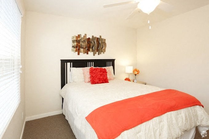 a bedroom with a white bed and an orange blanket