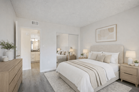 A well-lit bedroom with a large bed and a dresser.