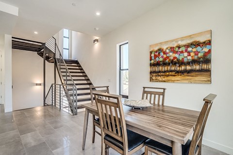 a dining room with a wooden table and chairs and a staircase