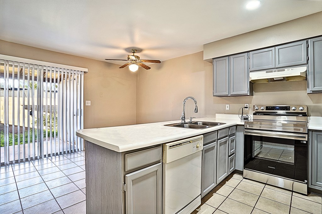A kitchen with a white counter top and stainless steel appliances.