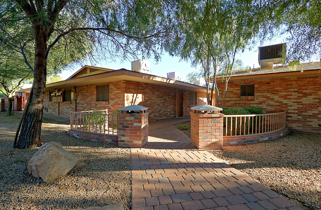 a brick house with a pathway and a tree