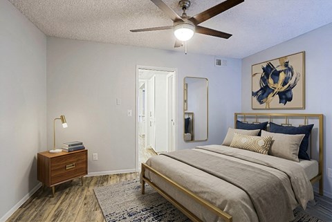 A bedroom with a bed, nightstand, and artwork on the wall.