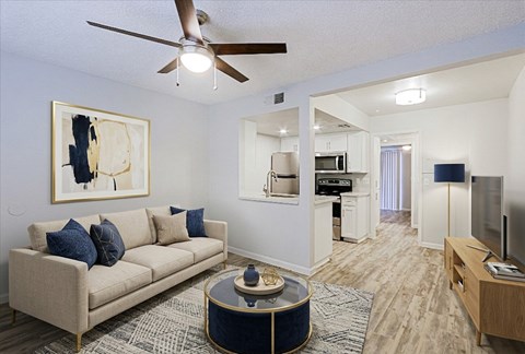 A living room with a beige couch, a coffee table, and a painting on the wall.