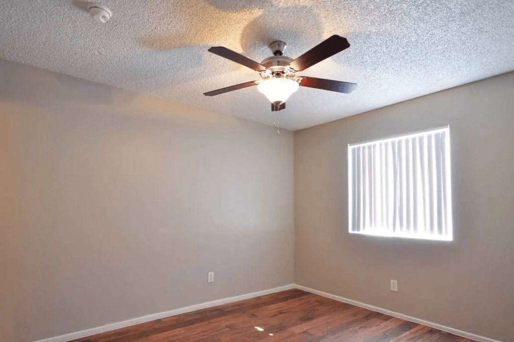 A room with a ceiling fan and a window with blinds at Gilbert Square Apartments, Mesa, AZ