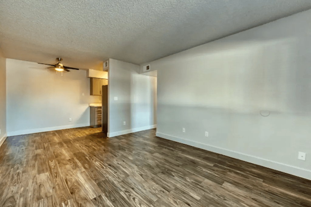 A room with wooden flooring and a ceiling fanat Gilbert Square Apartments, Mesa Arizona