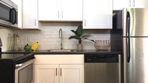 a kitchen with white cabinets and a black counter top