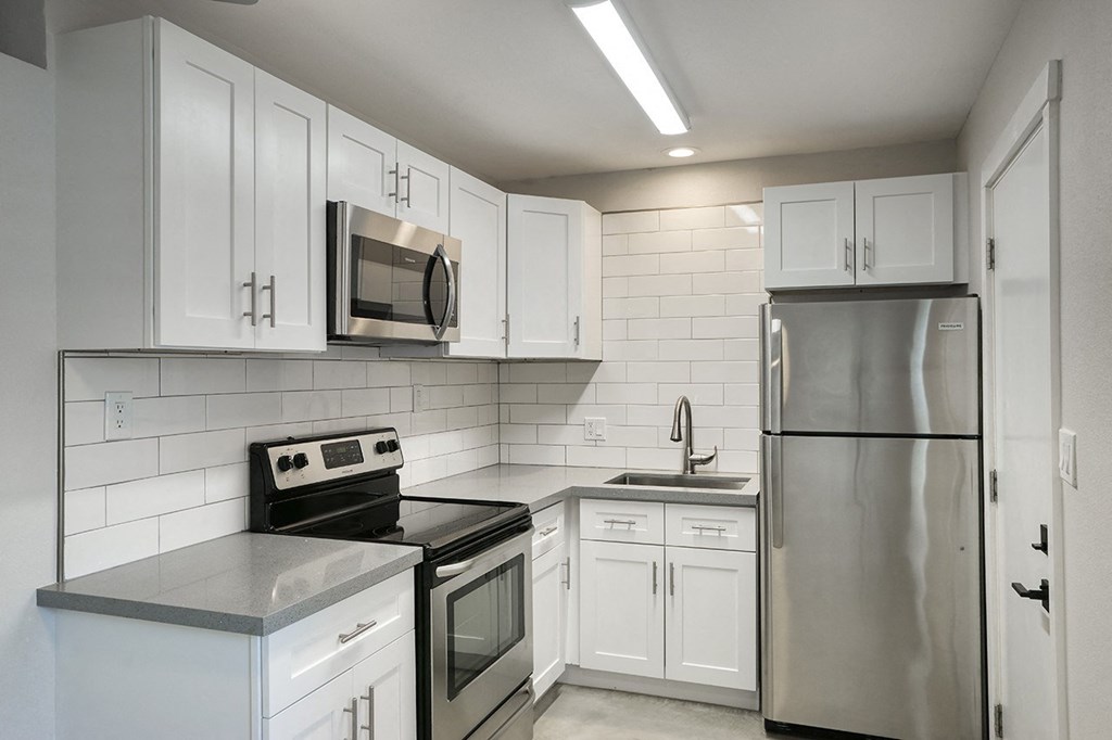 an empty kitchen with white cabinets and stainless steel appliances